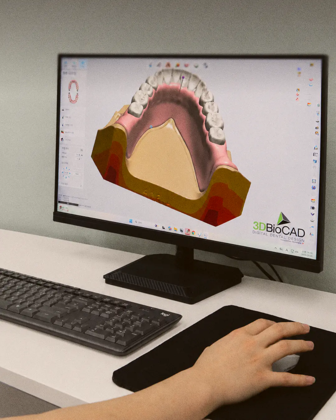 A hand on the mouse at the CAD screen with a scanned arch open