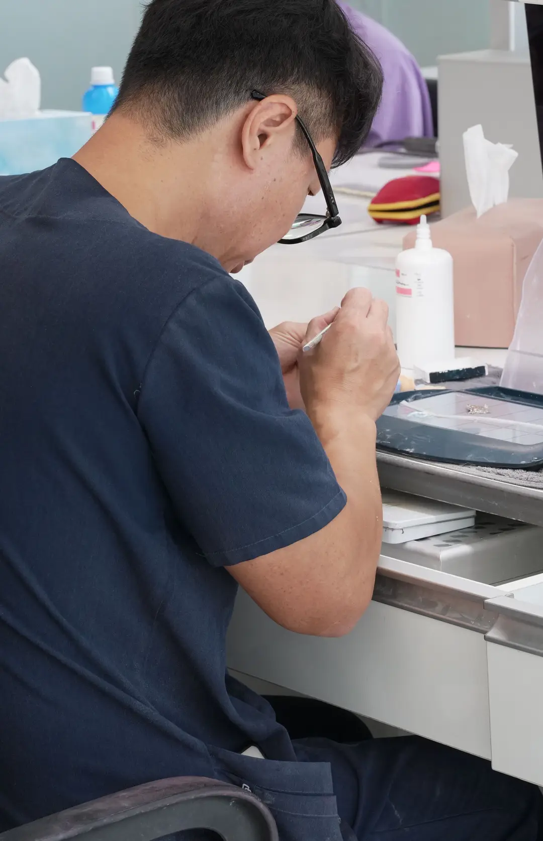 A master technician at his bench, head bent over the restoration in his hands
