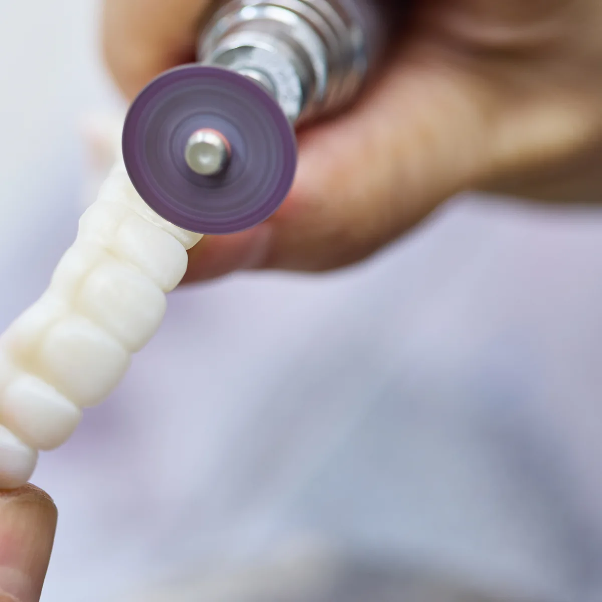 A master&rsquo;s gloved hands finishing a multi-unit piece with a polishing disc