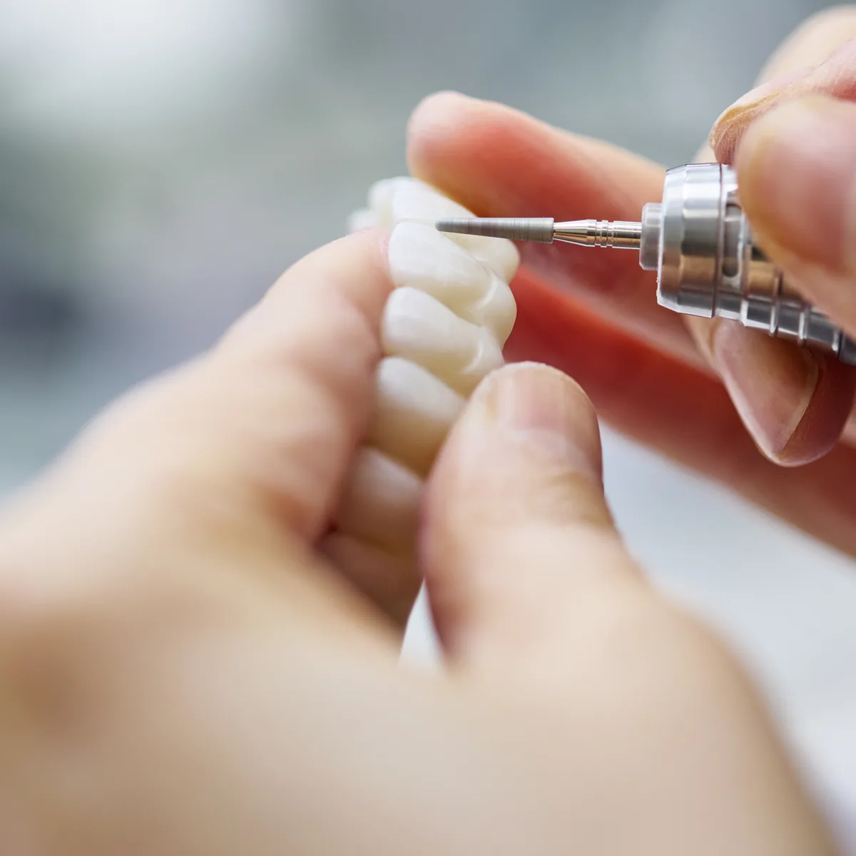 A small restoration held between two fingers against a fine bur