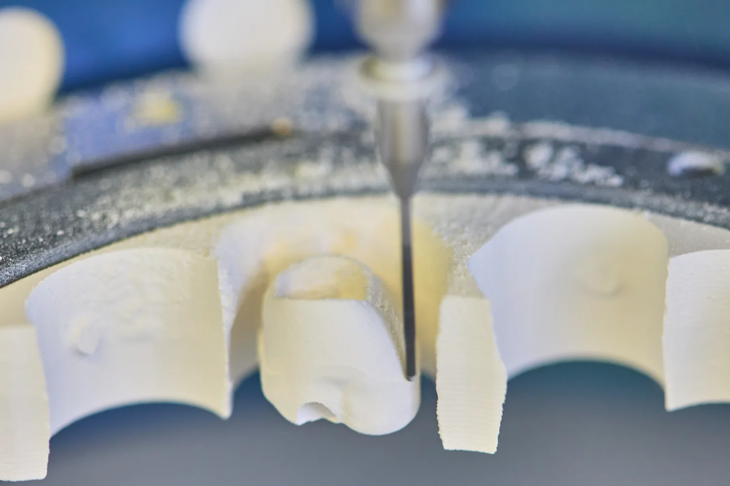 A restoration being milled out of a zirconia disc, the bur still in the block