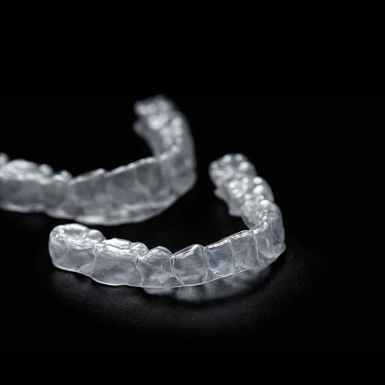 A pair of clear aligner trays, upper and lower, on a black ground