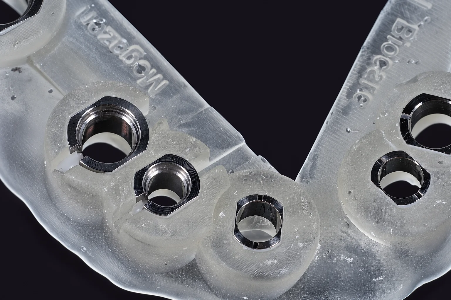 Close up of metal sleeves set in a clear printed guide, the implant system names printed on the resin