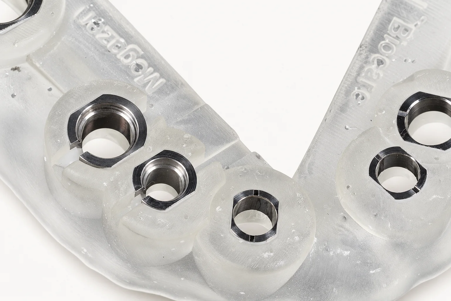 Close up of metal sleeves set in a clear printed guide, the implant system names printed on the resin