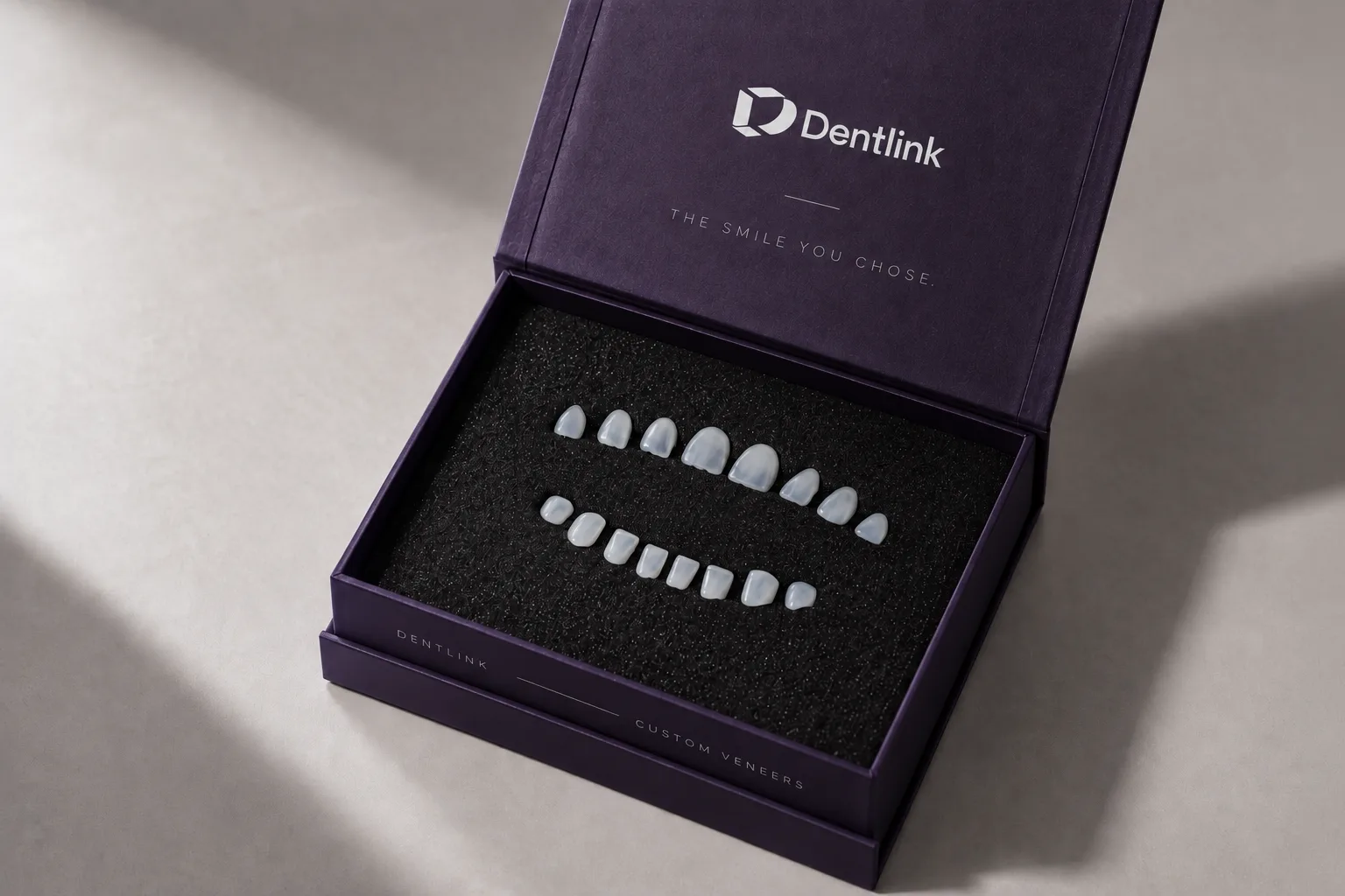 An open Dentlink presentation box with a full set of veneers laid in it